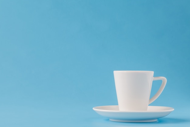 modern stylish white coffee mug on a plate on a blue background