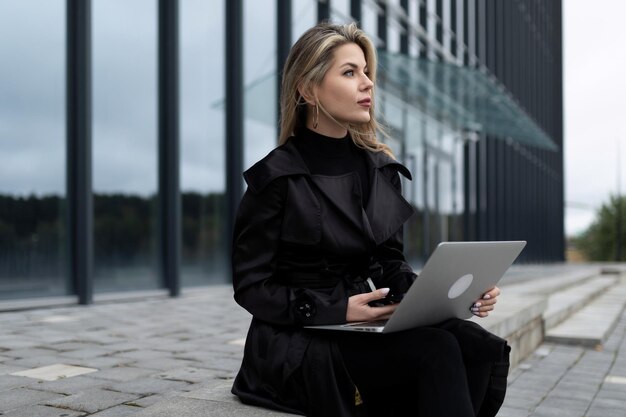 Modern successful business woman works online on the background of an office building