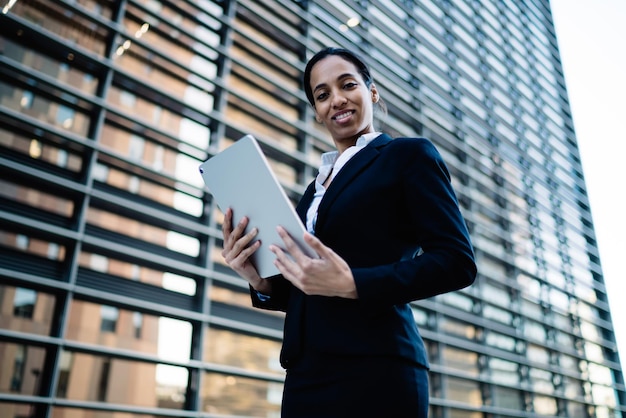 Modern successful businesswoman with tablet on street