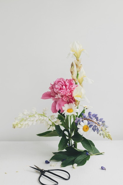 室内の素朴な白いテーブルにモダンな夏の花の組成 創造的な花のイメージ