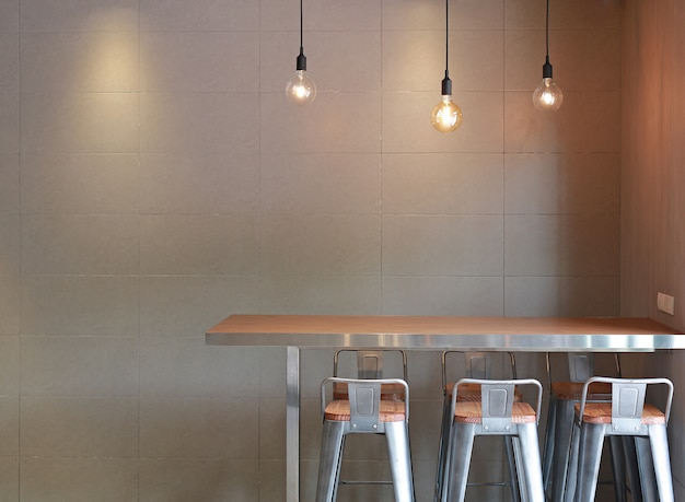 椅子がロフトの灰色のタイルの壁と吊り下げ用の燭台を備えたモダンなテーブルカウンターバー。