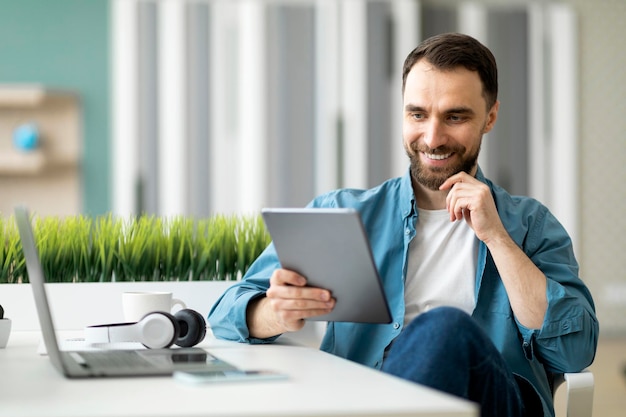 Modern technologies handsome smiling man using digital tablet in office