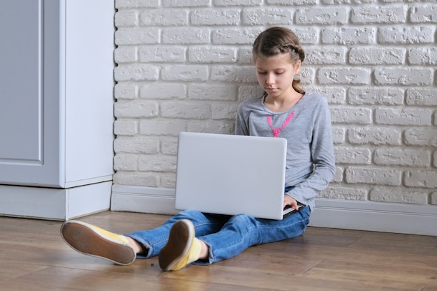 Modern technologies in peoples lives, girl child sitting at home with laptop computer