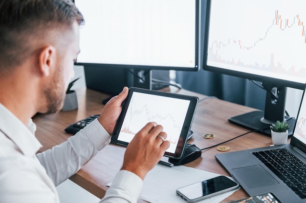 Modern technologies Young businessman in formal clothes is in office with multiple screens