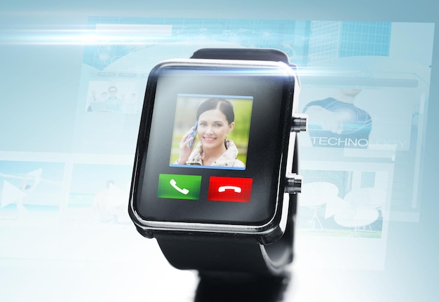現代のテクノロジー、コミュニケーション、オブジェクト、メディアのコンセプト – 青い背景にビデオ通話の連絡先アイコンとボタンが付いた黒いスマートウォッチの接写