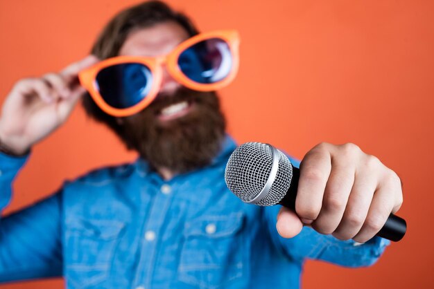 Modern technology male sing music in microphone funny bearded man with mic brutal hipster in party glasses karaoke singer unshaven guy with groomed long hair