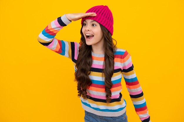 Modern teenage girl 12 13 14 year old wearing sweater and knitted hat on isolated yellow background happy teenager positive and smiling emotions of teen girl