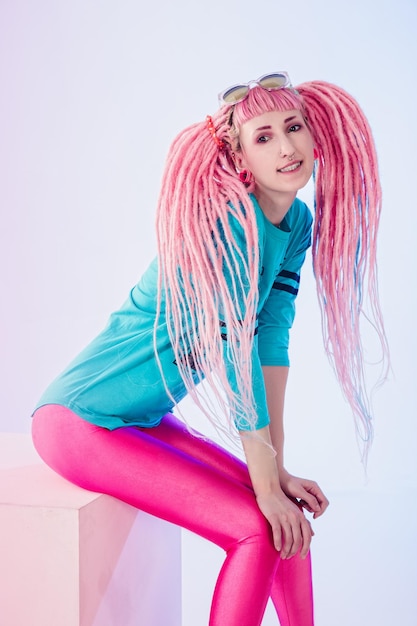 Modern teenage girl with pink dreadlocks on white background