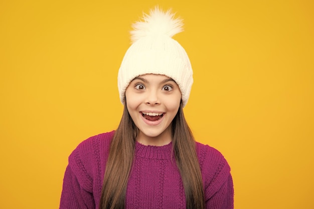 Foto modern tienermeisje die sweater en gebreide muts op geïsoleerde gele achtergrond dragen