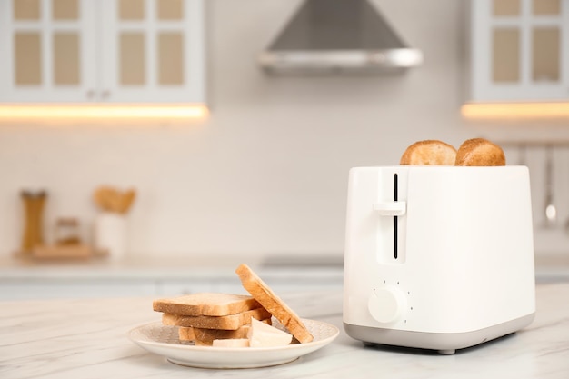 Современный тостер и ломтики хлеба на белом мраморном столе на кухне
