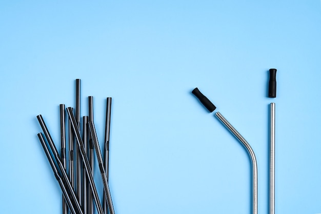 The modern trend towards caring for the environment. A pack of black plastic beverage straws versus only two reusable metal beverage straws with silicone cap.