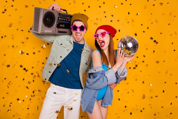 Foto tendenza moderna due persone studenti godono festa tenere cassetta record boom box discoteca palla coriandoli caduta volare indossare denim jeans giacca costume da bagno camicia pantaloncini isolato brillante brillante colore sfondo