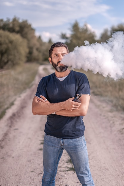 Vaper moderno che gode di un dispositivo elettronico per il fumo nella foresta