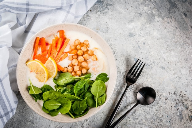 Modern veganistisch eten, hartige yoghurtkom met bonen, kikkererwten, spinazie, pittige wortelen, citroen