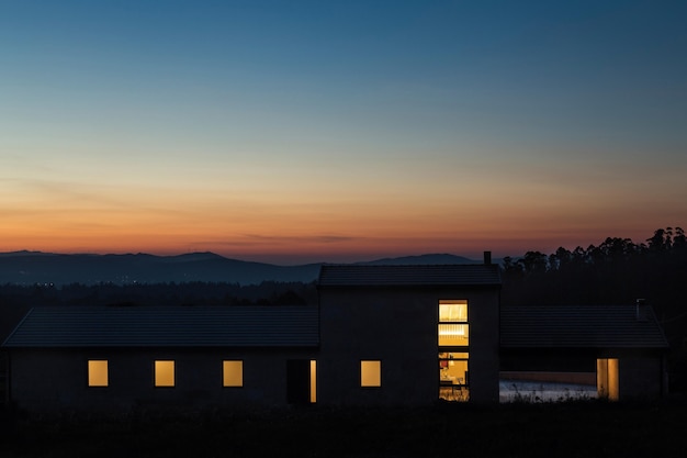 Foto esterno della villa moderna di notte con sfondo di montagna. scatto notturno della villa contemporanea