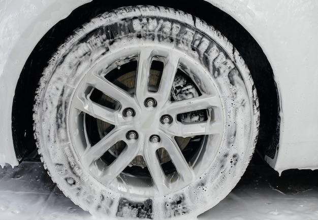 Modern washing of car wheels with foam and high water pressure. Car wash.