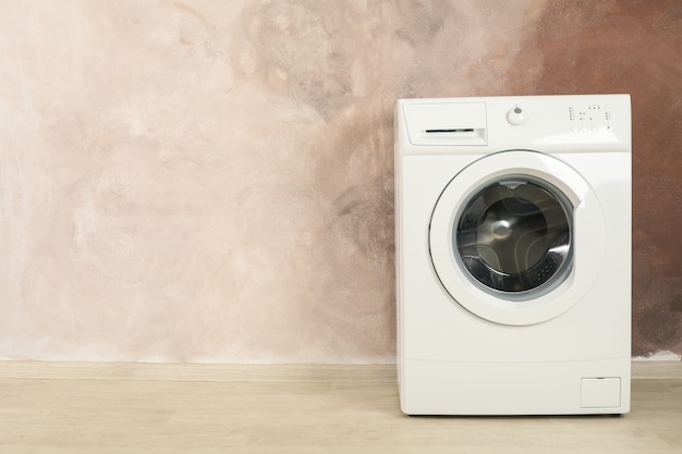 Modern washing machine against brown wall, space for text