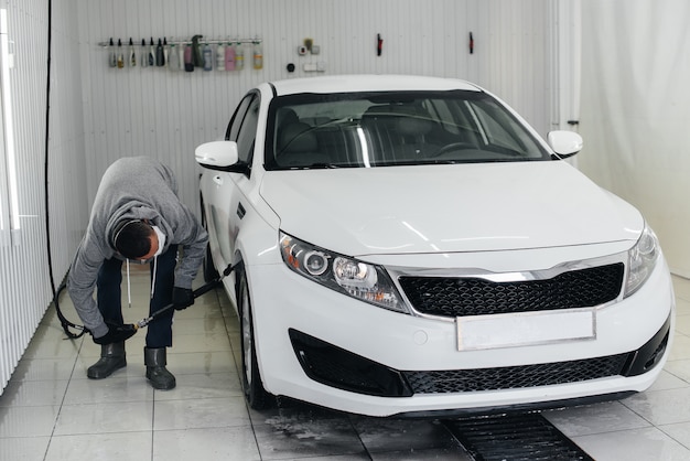 Modern wassen met schuim en water onder hoge druk van een witte auto. Carwash.