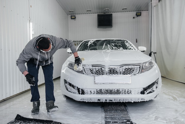 Modern wassen met schuim en water onder hoge druk van een witte auto. Carwash.