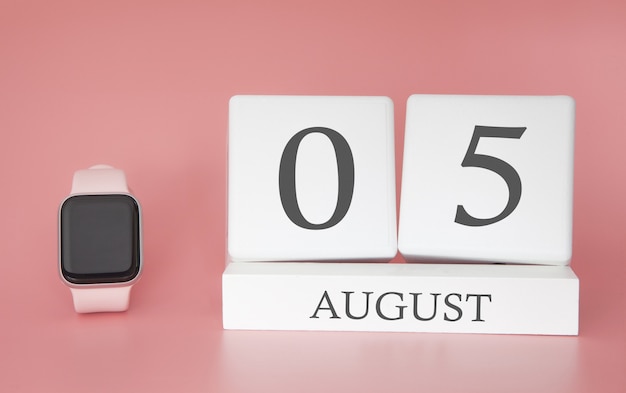 Orologio moderno con calendario cubo e data 05 agosto sulla parete rosa. vacanze estive concetto.