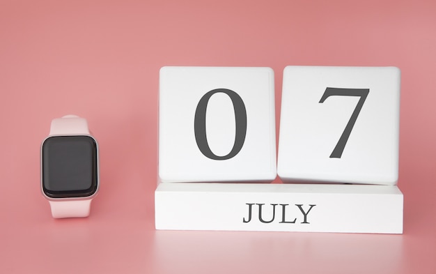 Orologio moderno con calendario cubo e data 07 luglio sulla parete rosa. vacanze estive concetto.
