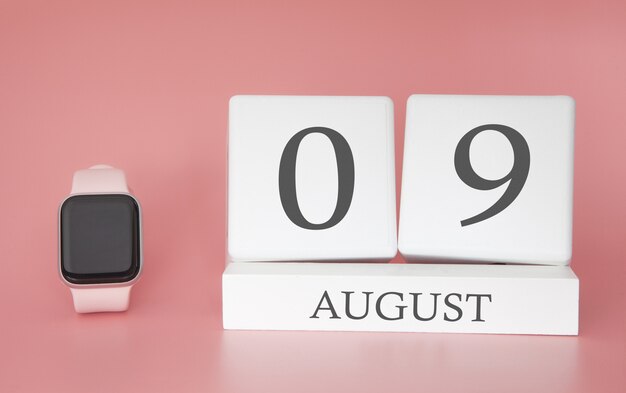 Modern Watch with cube calendar and date 09 august on pink wall. Concept summer time vacation.