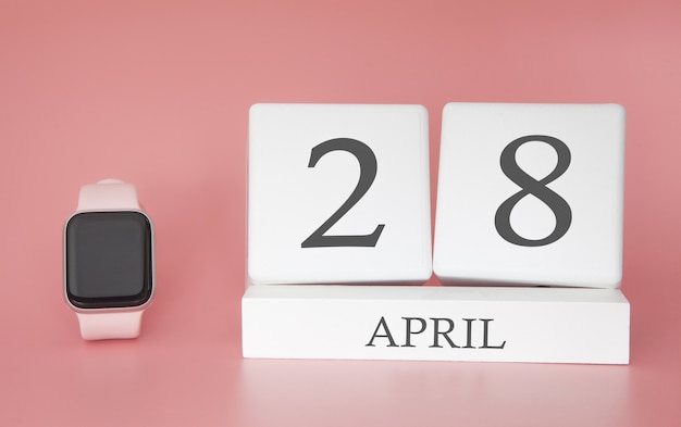 Современные часы с календарем куб и датой 28 апреля на розовом фоне. Концепция весеннего времени отпуска.