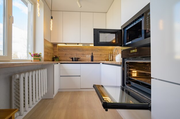 Modern white and beige wooden kitchen interior with oven opened