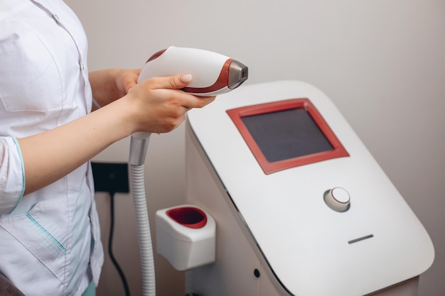 A modern white big cosmetic apparatus for skin care and spa treatments. Improve and therapy the skin in the salon. A woman in a white uniform gets to work.The concept of spa procedure .