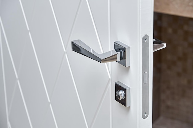 Modern white door with geometric rhombic pattern and chrome handle in house bathroom