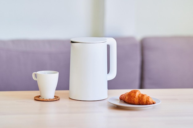 Modern white electric kettle for brewing tea on table at home