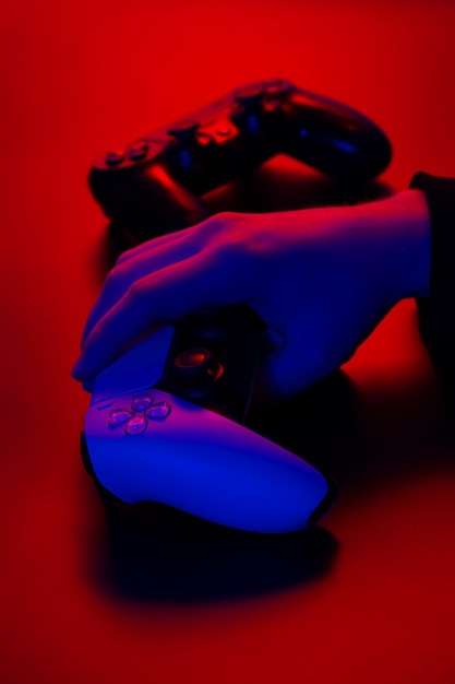 Foto gamepad bianco moderno illuminato di rosso e blu nelle mani maschili su un controller di gioco con sfondo scuro per videogiochi