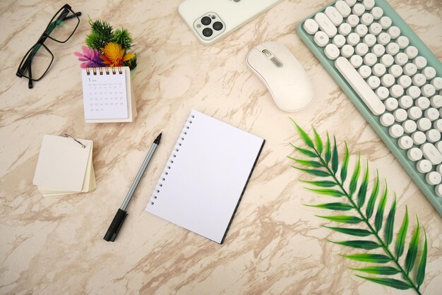 Modern white marble office desk table with keyboard smartphone and other supplies with stand calend