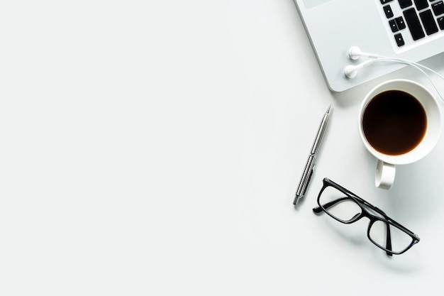 Modern white office desk table with laptop, cup of coffee and supplies. 