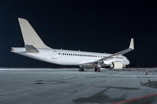 Moderno aereo passeggeri bianco sul piazzale dell'aeroporto notturno