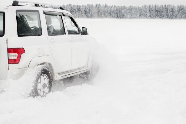 Modern white Suv car on snowy road when driving through snowdrifts.