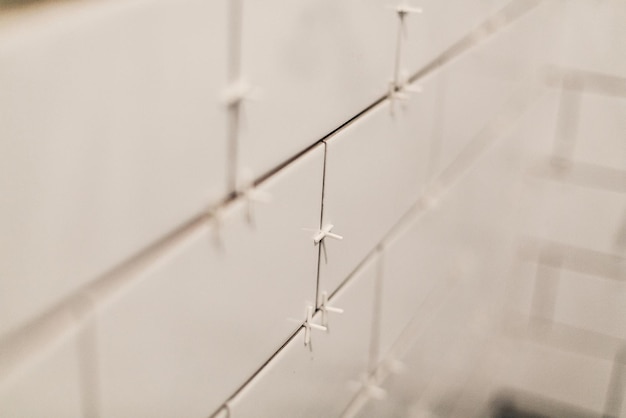 현대적인 흰색 타일 리노베이션 개념 세라믹 타일, 스페이서 및 회색 시멘트 벽이 있는 욕실 리노베이션 및 텍스트 수리를 위한 화장실 공간 작업