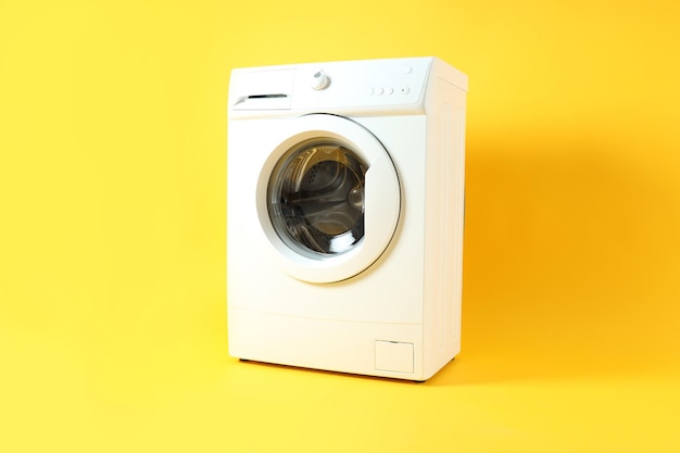 Modern white washing machine on yellow background