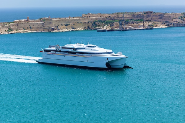 A modern white yacht on the background of beautiful coastline with traditional buildings 