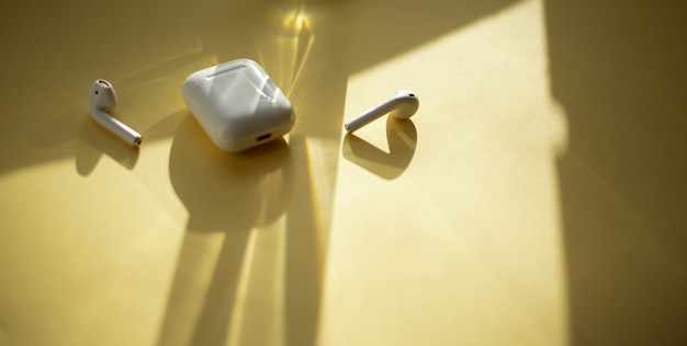 modern wireless earphones on a pastel yellow background