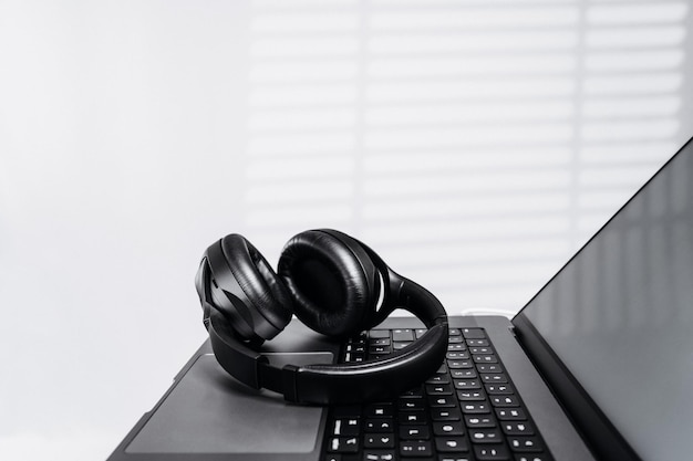 Modern wireless headphones over the laptop computer while taking break Workspace or home office of programmer or freelancer Online remote working distant learning work from anywhere concept