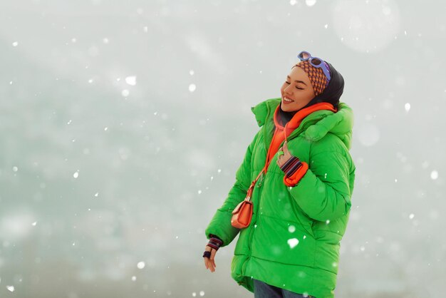 Modern woman in hijab with green jacket posing on a winter day