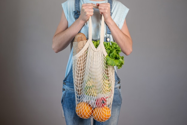 La donna moderna in jeans sta tenendo una borsa a tracolla con gli acquisti