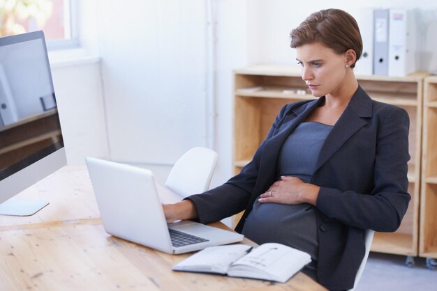 Modern women can do it all A pregnant businesswoman working on a laptop at her office desk