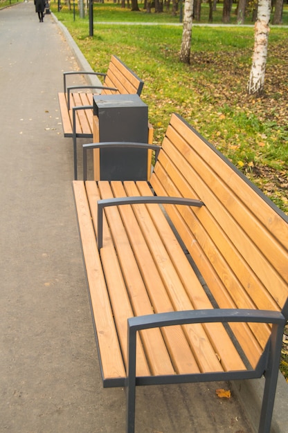 Modern wooden bench and urn in the autumn park, vertical photo.