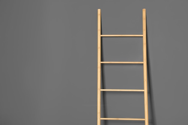 Modern wooden ladder on grey background Space for text