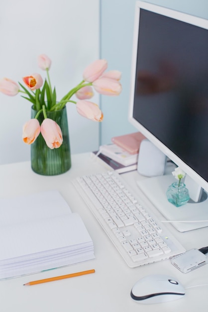 Modern workplace in light room with blue walls Bouquet of pink tulips on the table Feminine workspace