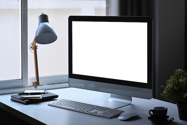 Modern workplace with computer lamp coffee cup and houseplant