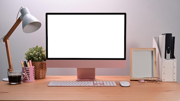 Modern workplace with computer pencil holder houseplant and lamp on wooden table