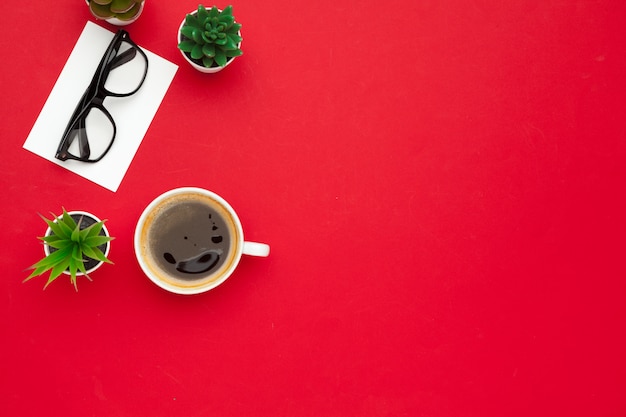 Modern workplace with cup of coffee, red background, top view